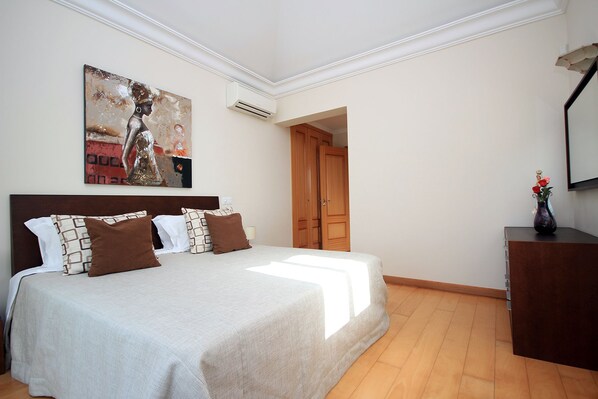 Une chambre avec un grand lit, une armoire en bois et un tableau accroché au mur.