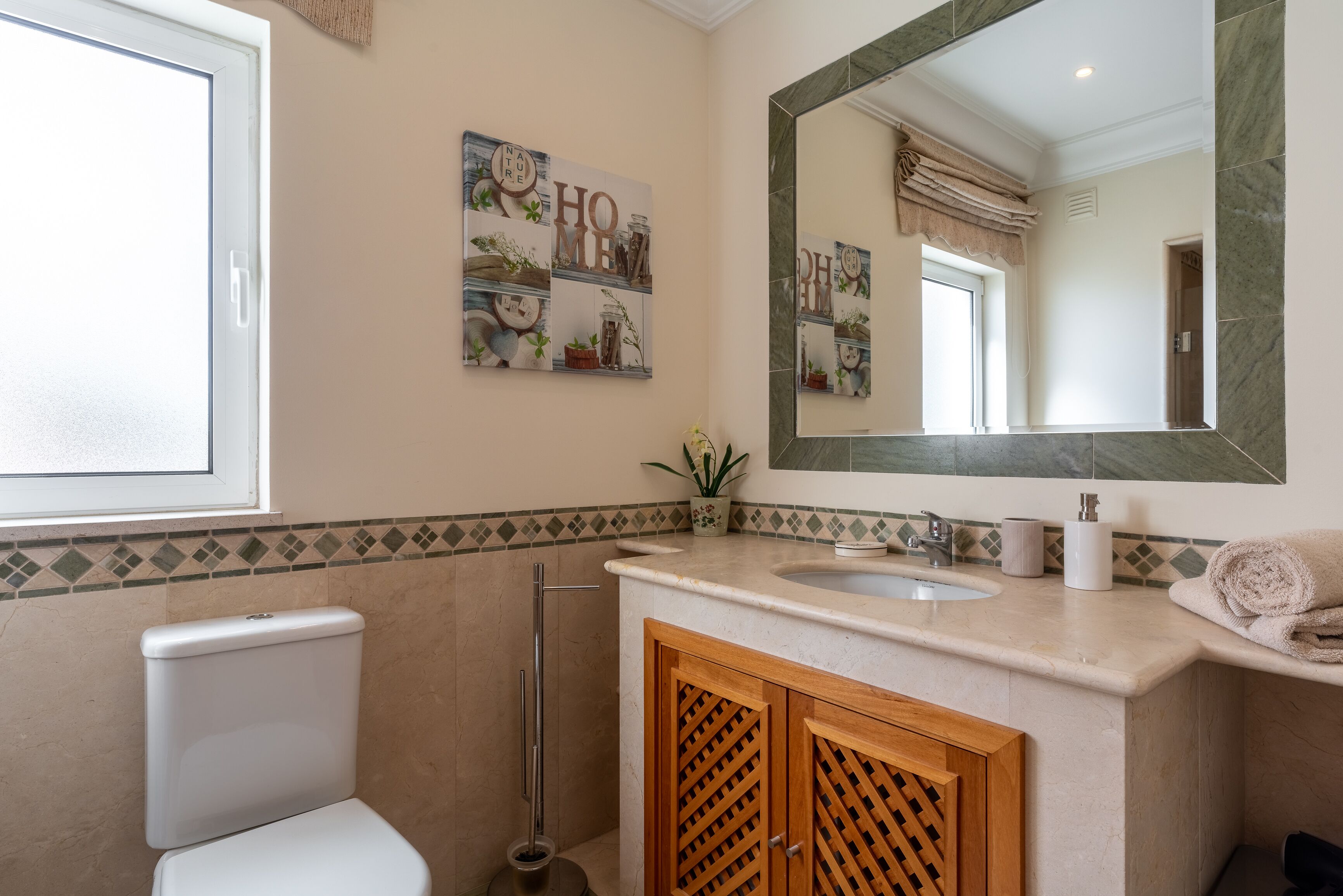 Une salle de bain équipée de toilettes, d’un lavabo, d’un miroir et d’œuvres d’art décoratives sur les murs.