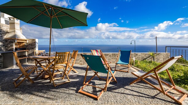 Una terrazza con mobili in legno, un ombrellone verde e vista sul mare.