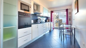 Una cucina moderna con mobili bianchi, forno integrato e zona pranzo con tavolo e sedie.