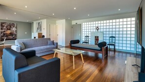 A modern living room with a sofa, a coffee table, and a TV stand. - Villa Nogueira IV (Funchal)