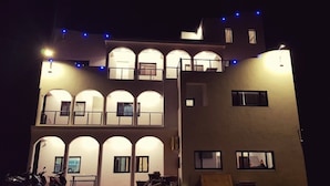 A multi-story building with balconies and arched windows, illuminated at night. - Polaris B&B (Magong)