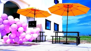 A white building with a balcony, outdoor seating area, and a view of the sea. - Polaris B&B (Magong)