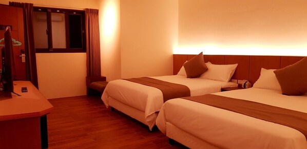 Habitación de hotel con dos camas, un escritorio y una ventana con cortinas.