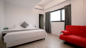 A modern hotel room with a bed, a red sofa, a window with curtains, and a skylight. - Polaris B&B (Magong)
