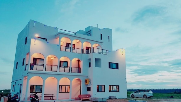 A modern two-story building with balconies and a car parked in front. - Polaris B&B (Magong)