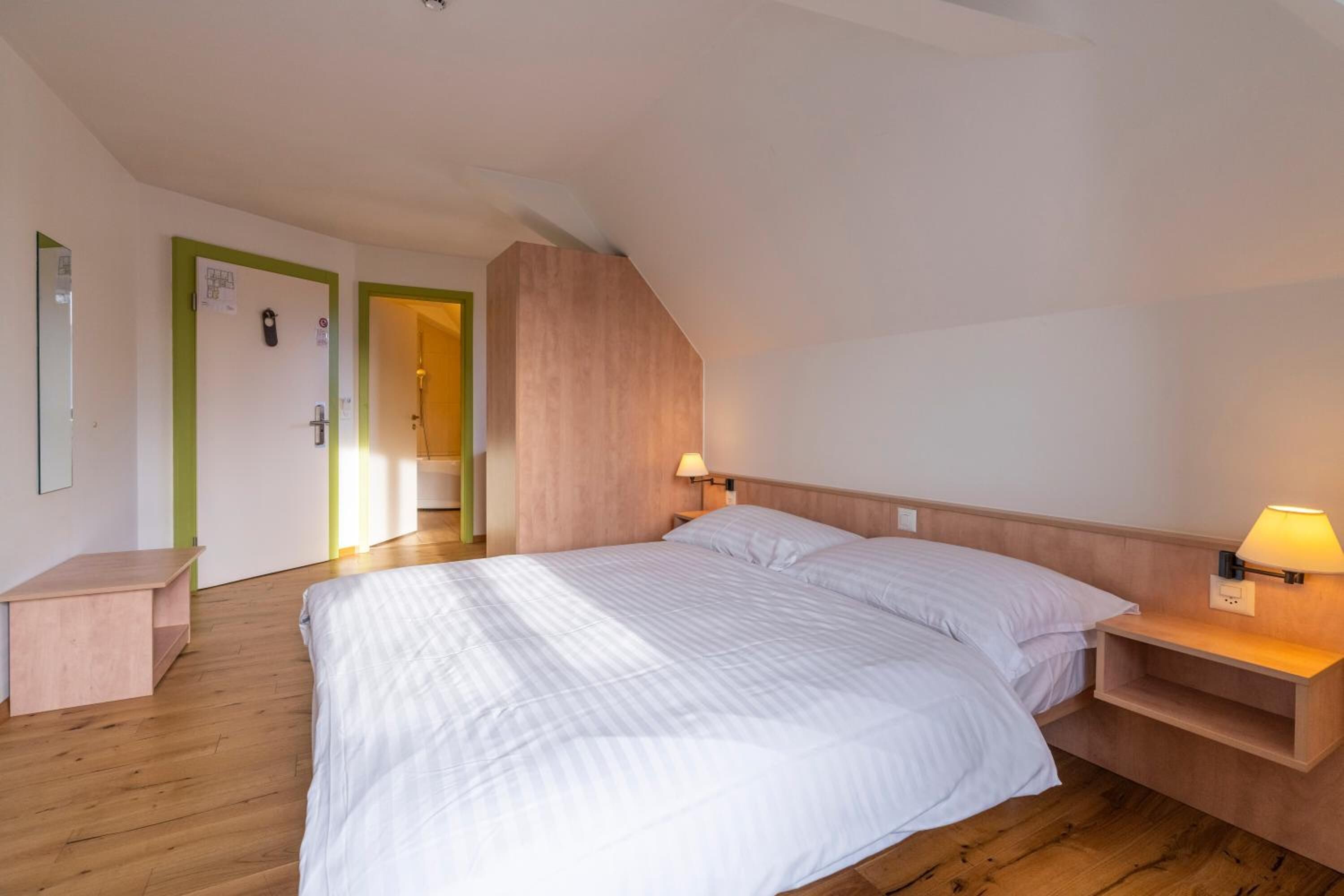 Un dormitorio con una cama grande, mesitas de noche, un cabecero de madera y una puerta con marco verde.