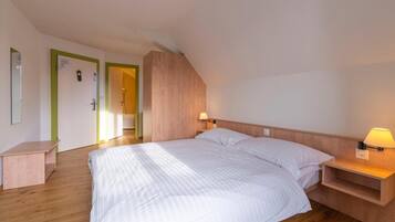 Un dormitorio con una cama grande, mesitas de noche, un cabecero de madera y una puerta con marco verde.