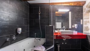Un baño moderno con una bañera grande, un tocador rojo y un espejo.