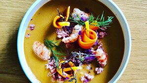 Un tazón de sopa con guarniciones sobre una mesa de madera.