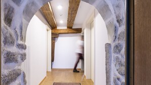 Un pasillo con pared de piedra, vigas de madera y piso de madera.