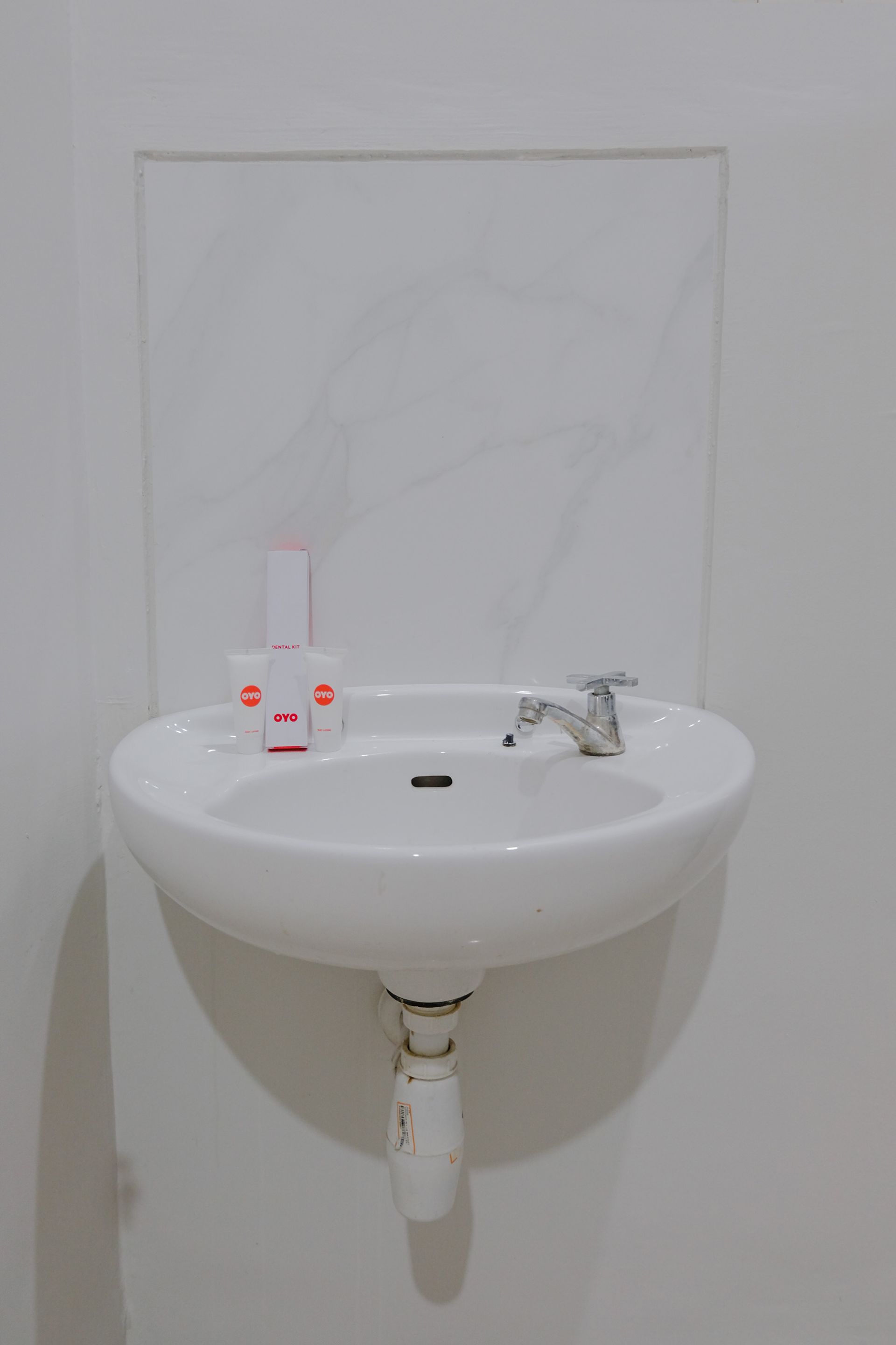 A white bathroom sink with a mirror above it, a faucet, and two OVO branded soap dispensers.