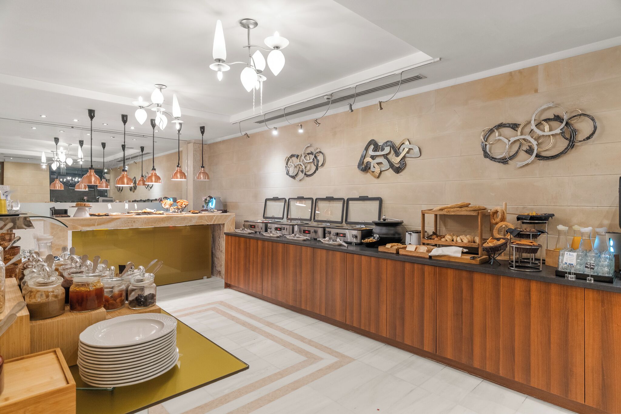 A hotel breakfast area with a wooden counter, various food items, and decorative wall art.