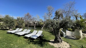 A poolside area with white lounge chairs and a tree. - Villa Louise-Rose (Villeneuve-Loubet)