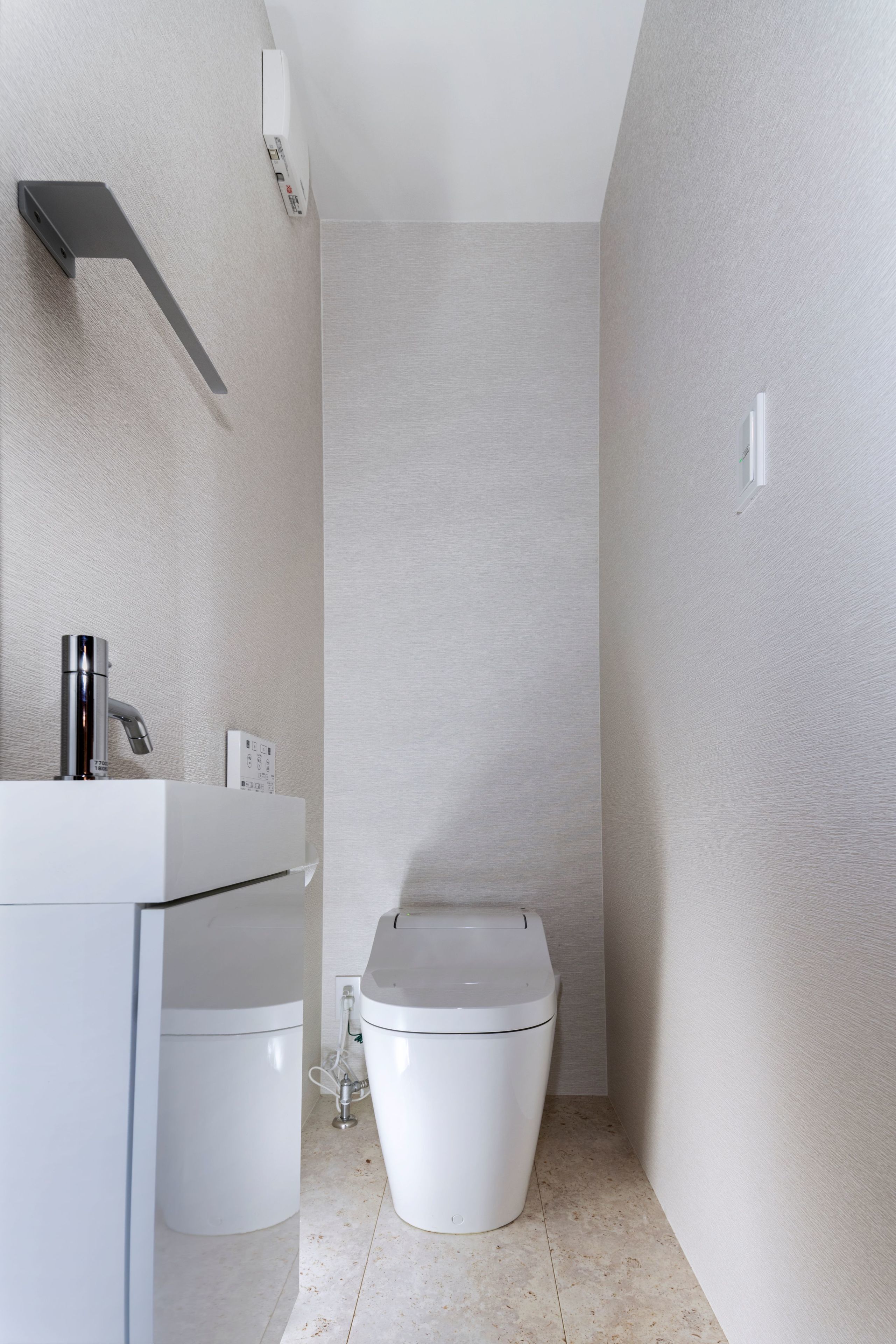 A modern bathroom with a white sink, a toilet, and a shower area.
