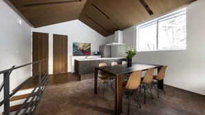 A modern kitchen with a central island, wooden ceiling, and a large window providing natural light. - Grey Wolf Chalet (Hakuba)