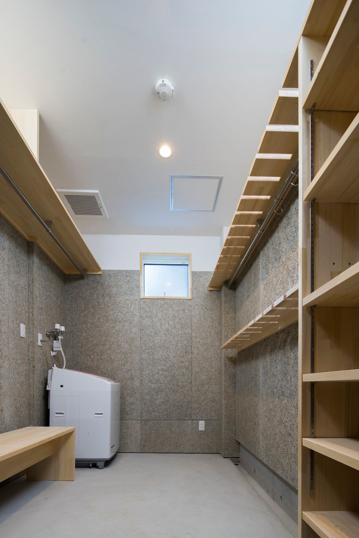 A room with a built-in washer and dryer, a skylight, and wooden shelving.