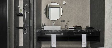 Un baño moderno con ducha de vidrio, lavamanos de mármol y un espejo grande.