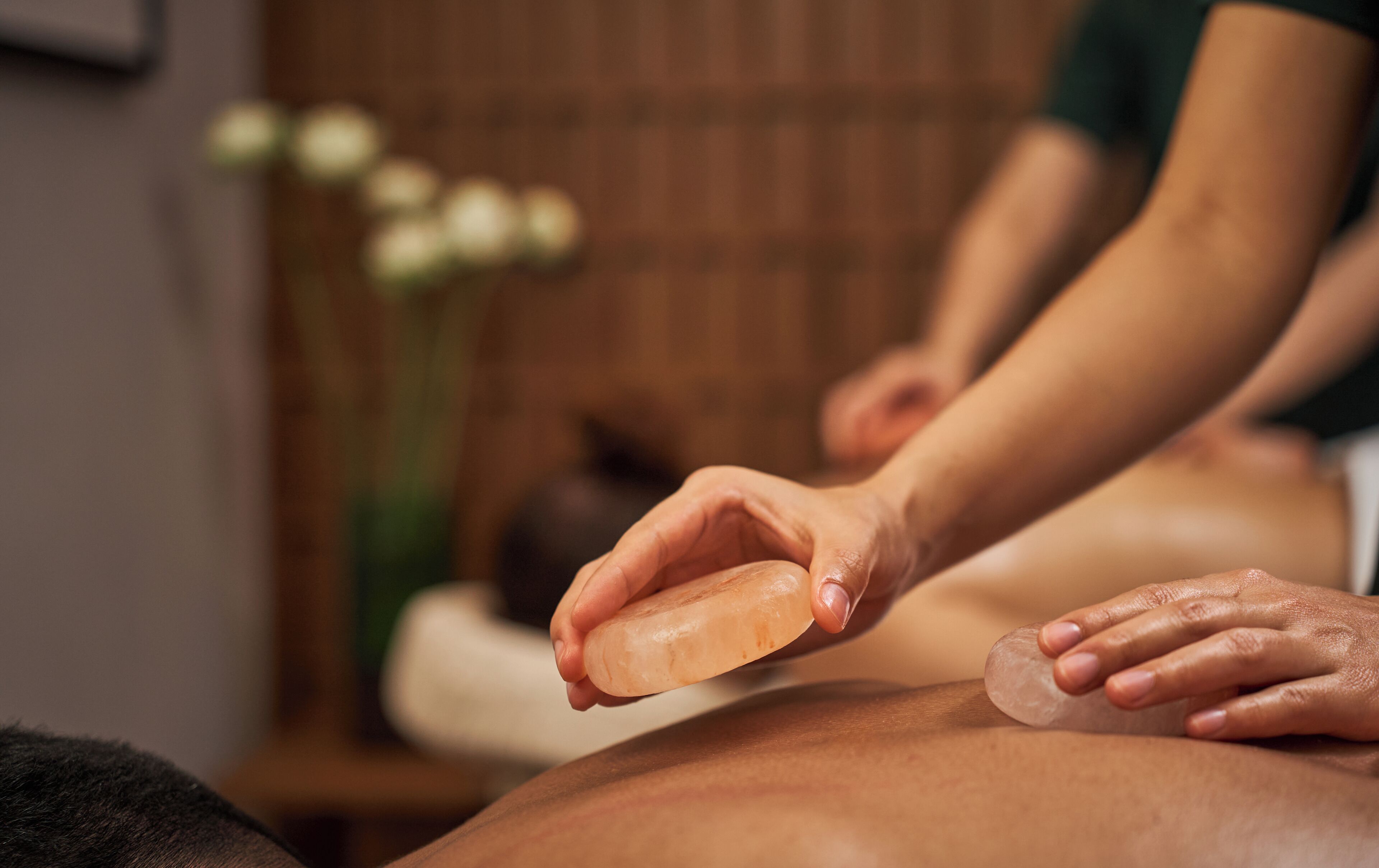 A massage therapy session with a focus on hands applying a treatment to a client's back.