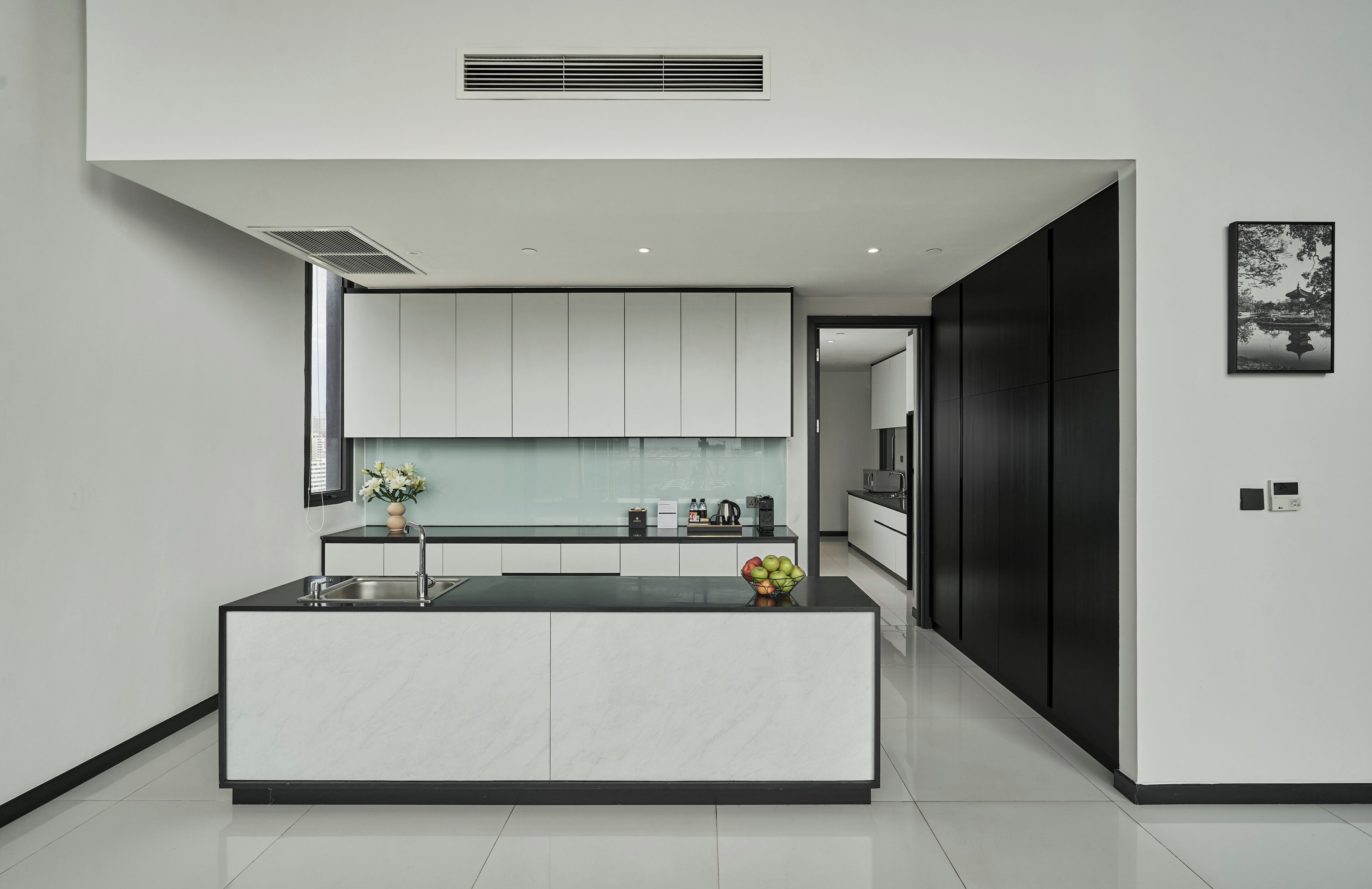A modern kitchen with a central island, white cabinetry, and a black accent wall.