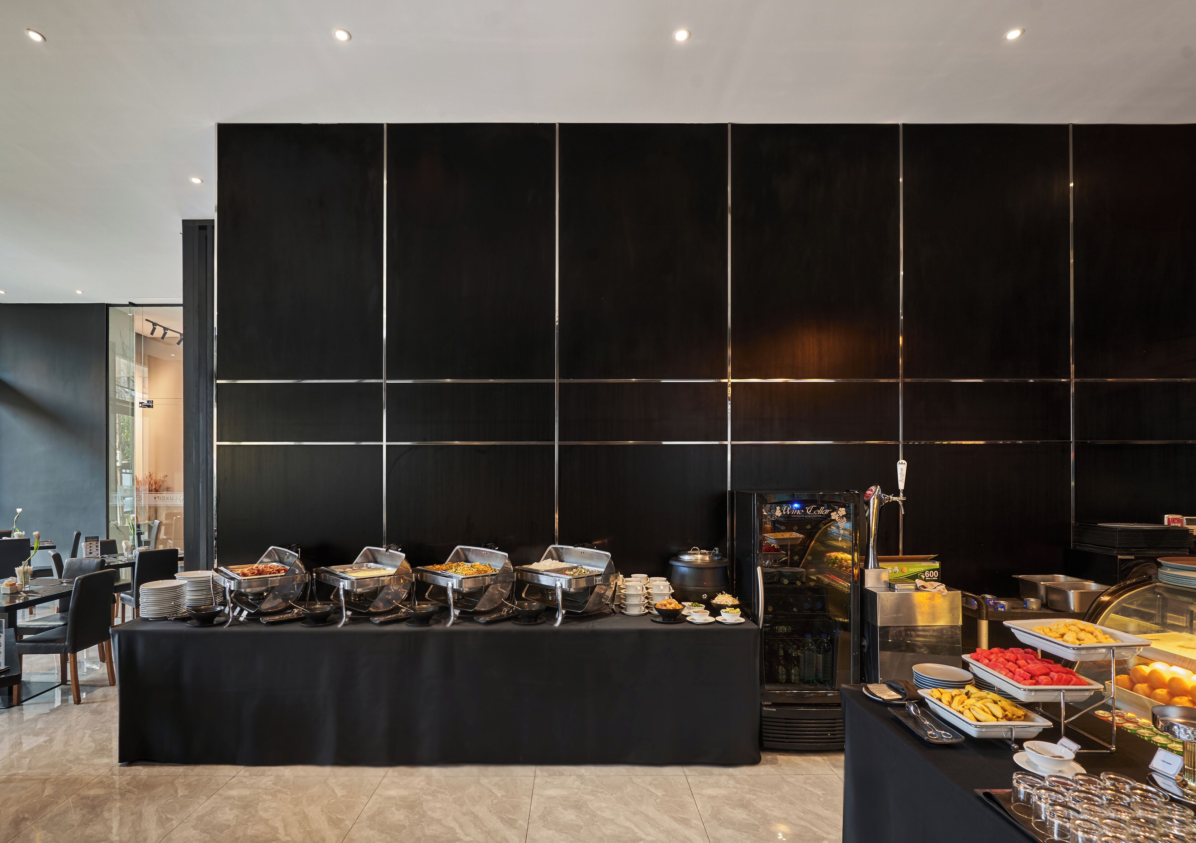 Mesa de buffet con diferentes alimentos y una vitrina de vidrio.