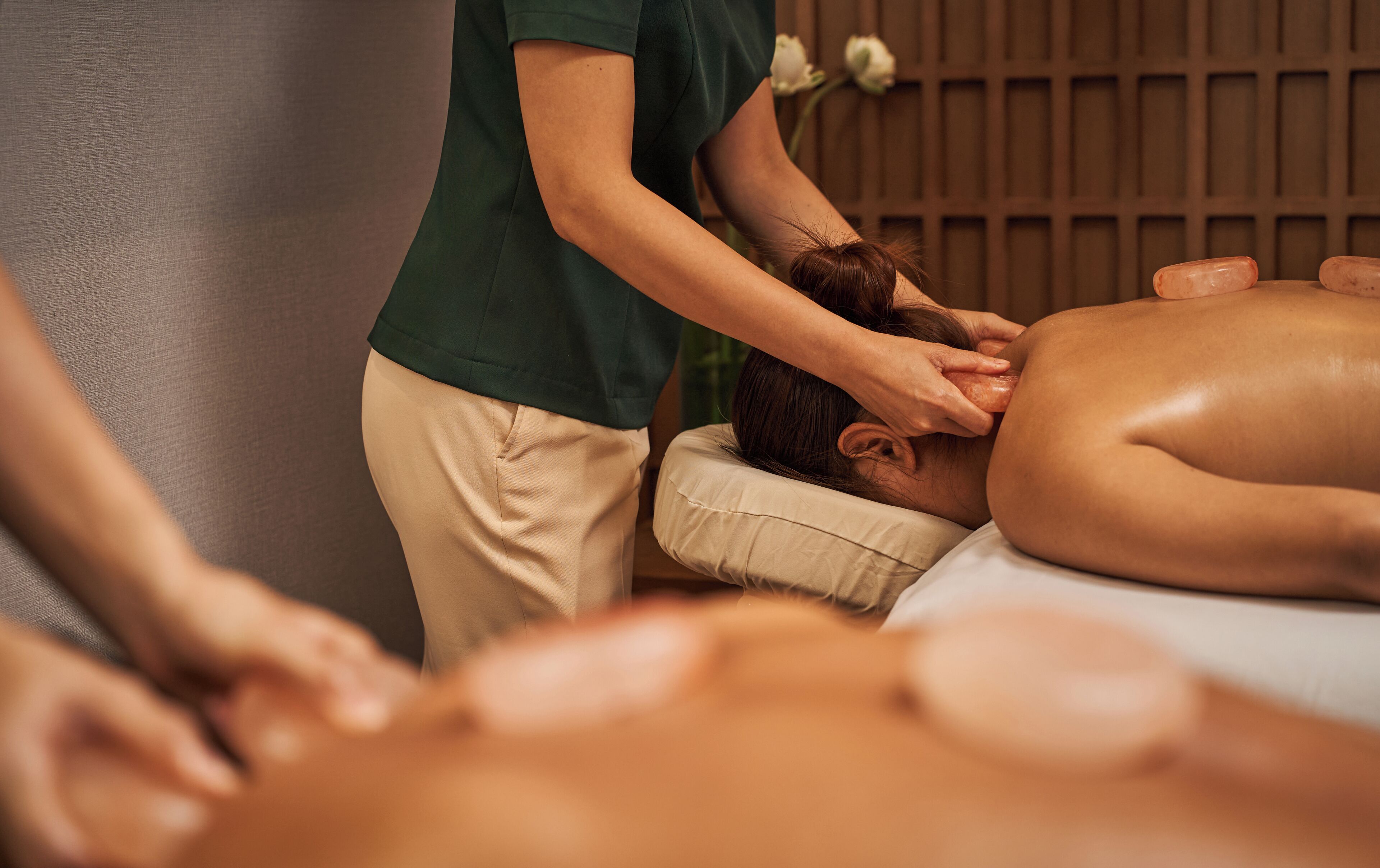 A massage therapy session in a room with a wooden panel wall and a massage table.