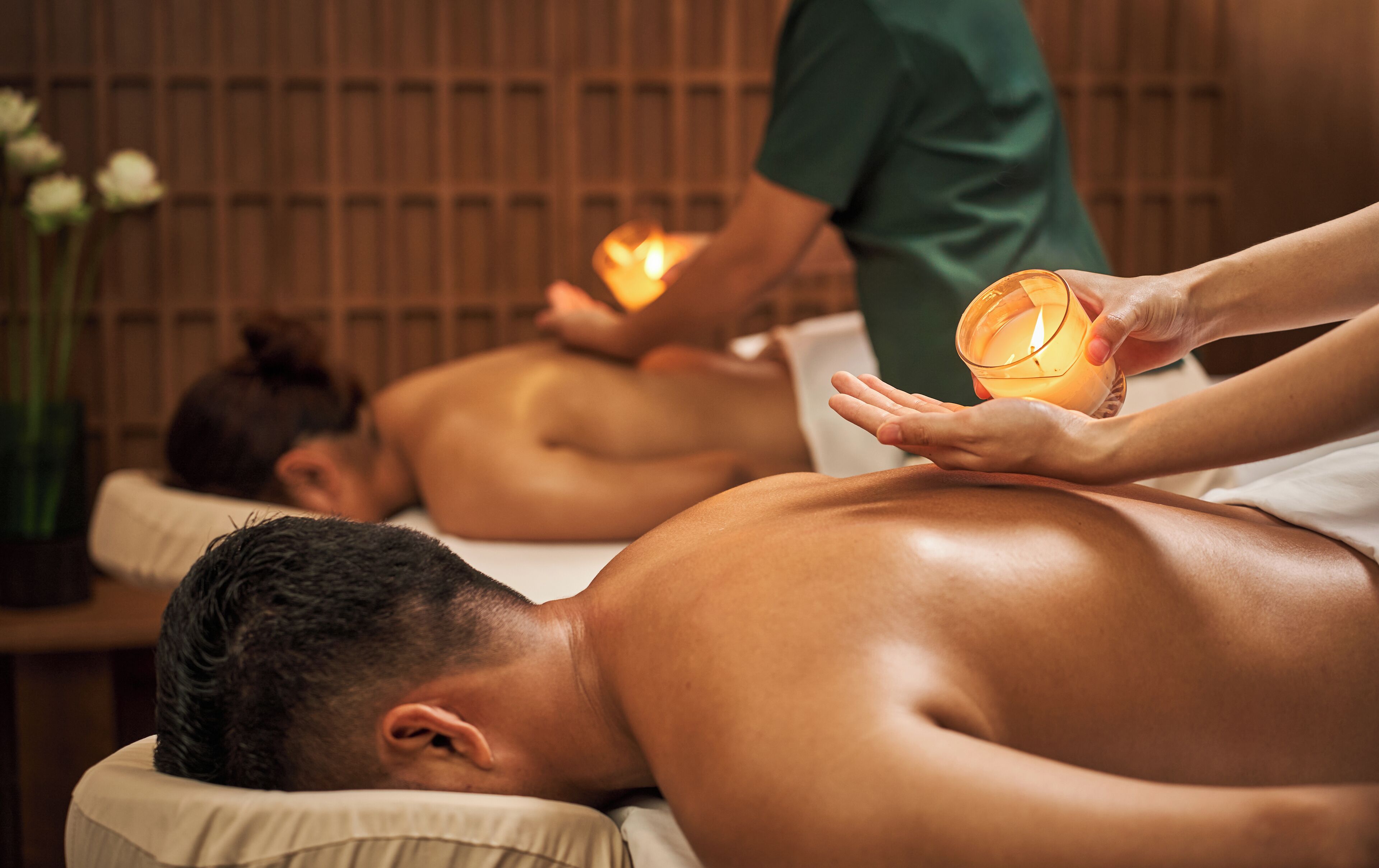 A massage therapy session with candles in a dimly lit room.