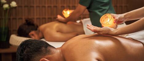 A massage therapy session with candles in a dimly lit room.