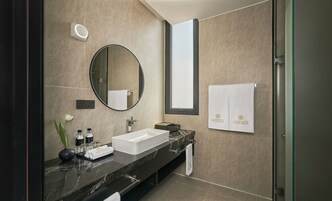 Een moderne badkamer met een marmeren wastafel, een grote spiegel en een handdoekrek met merkhanddoeken.