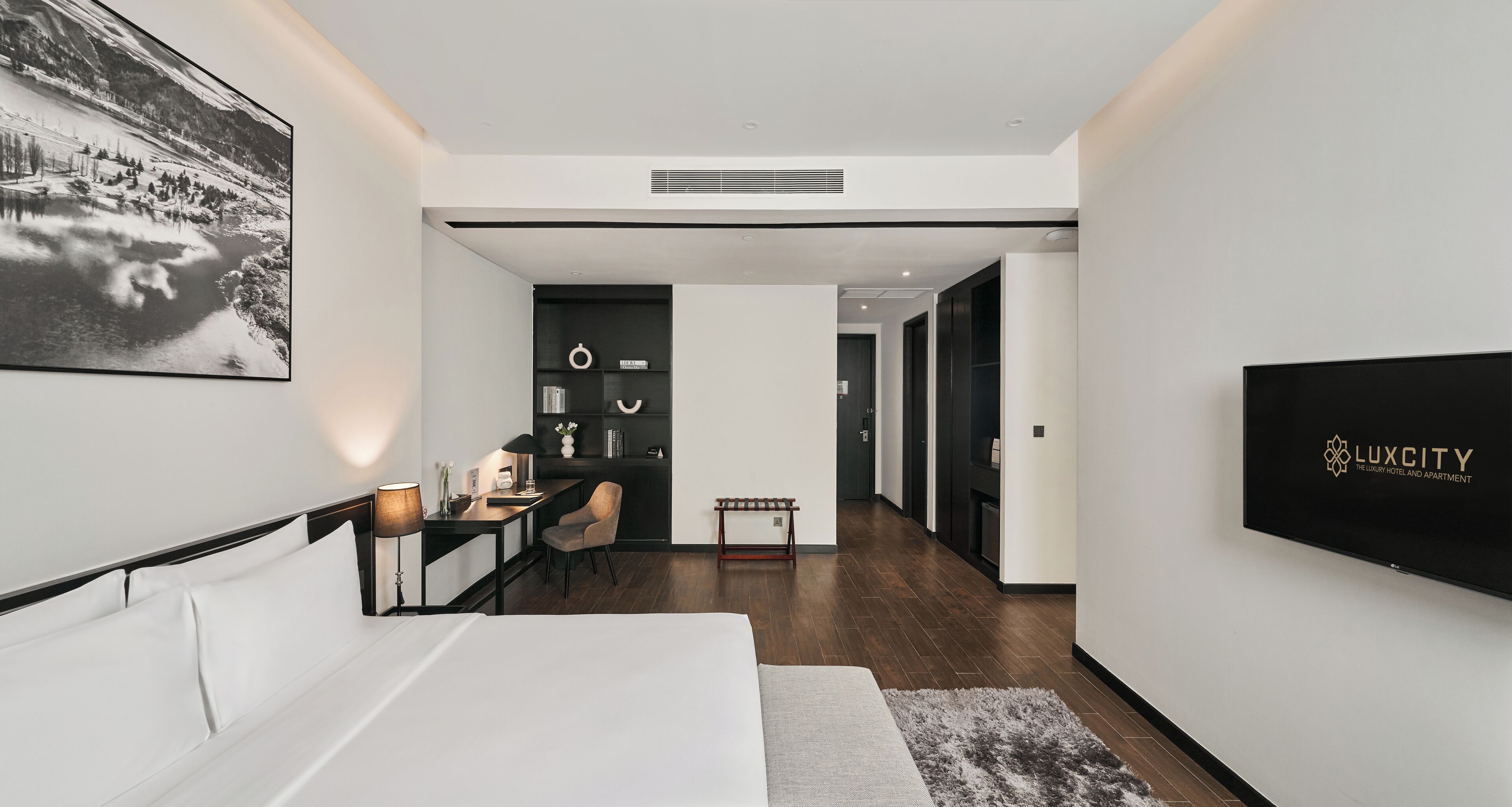 Una habitación de hotel moderna con una cama, un escritorio, una silla, un televisor y un cuadro en la pared.