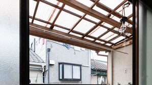 Habitación con un ventanal grande que da a un espacio exterior techado con techo de madera y lámpara colgante.