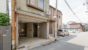Un edificio residencial con vestíbulo empinado, señal de límite de velocidad, coches estacionados y una bicicleta.