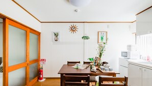 Un comedor con una mesa de madera, sillas, un extintor y una zona de cocina con microondas.