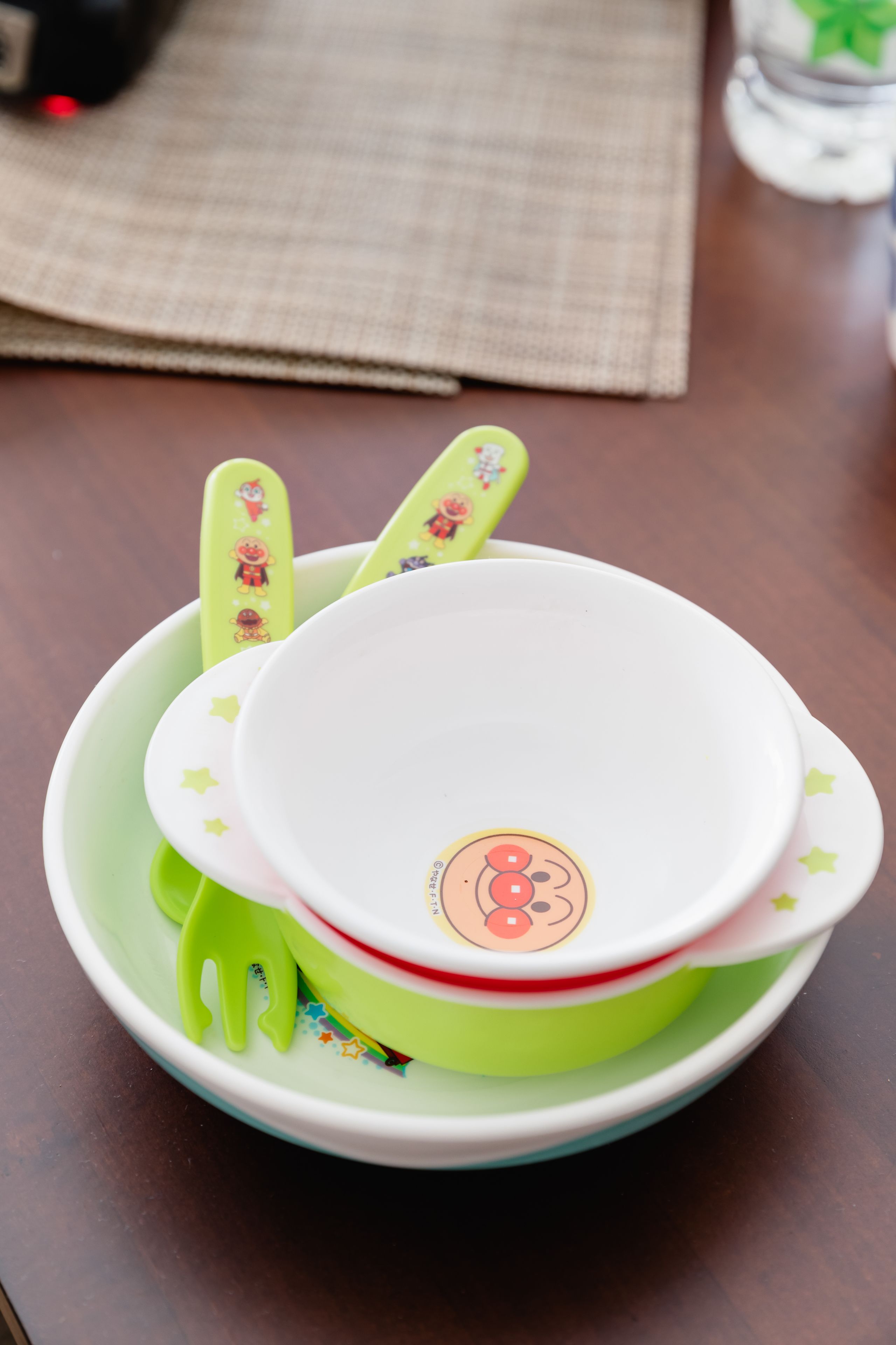 Une pile de bols verts et blancs ornés de motifs de dessins animés, posée sur une table en bois.