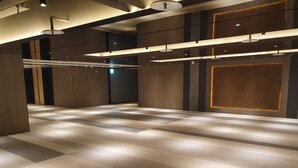 A spacious lobby with a checkered floor pattern, recessed lighting, and a modern design with wooden paneling and a large wall panel.