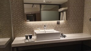 A modern bathroom with a white sink, a mirror above it, and a towel rack.