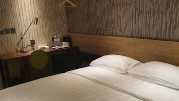 Habitación de hotel con una cama grande, un escritorio con silla, una lámpara colgante y un cabecero de madera.