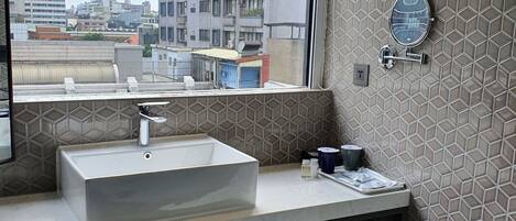 Un baño moderno con un ventanal grande, un lavamanos, un espejo y un inodoro.