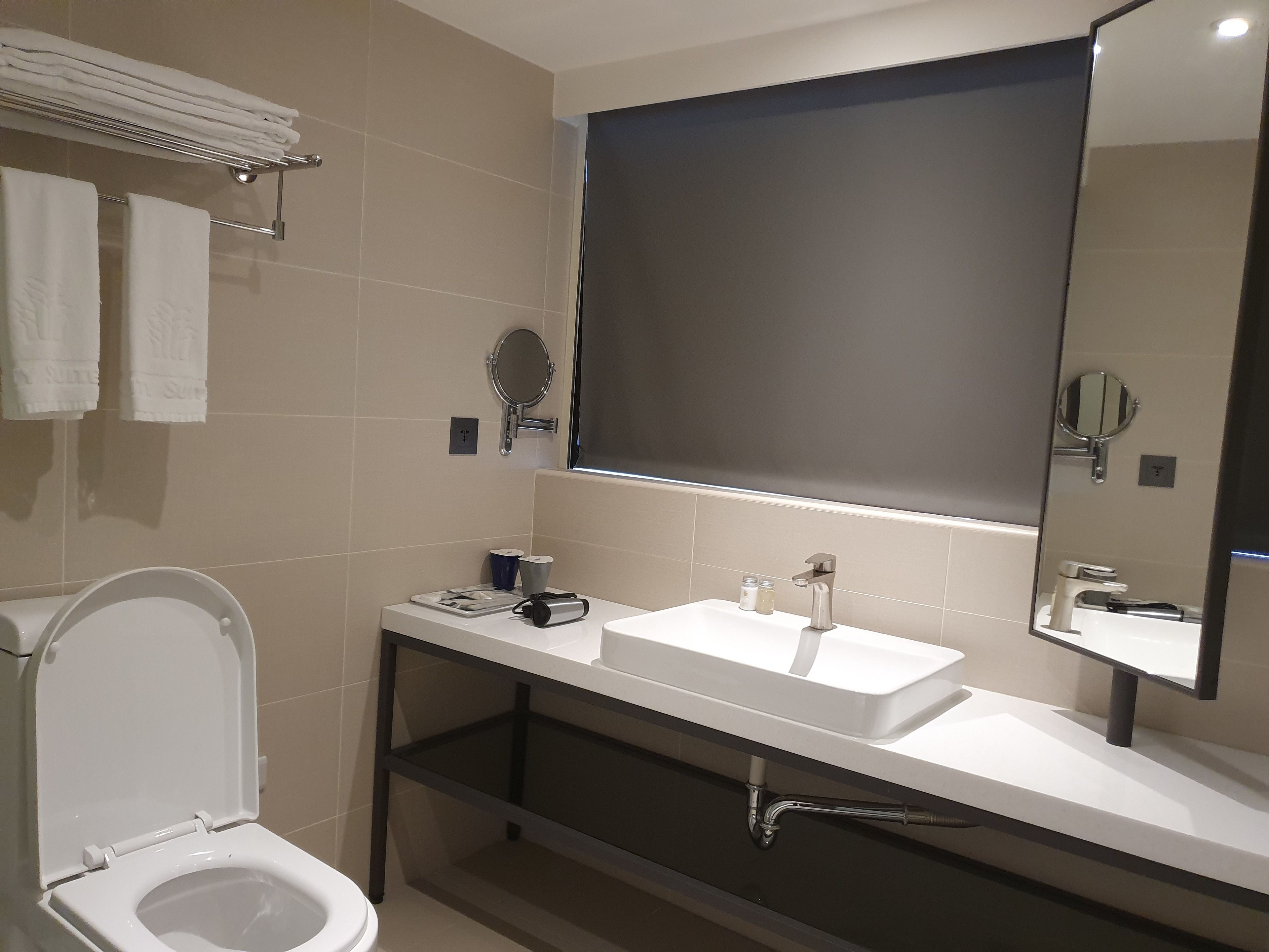 Een moderne badkamer met toilet, wastafel en grote spiegel.