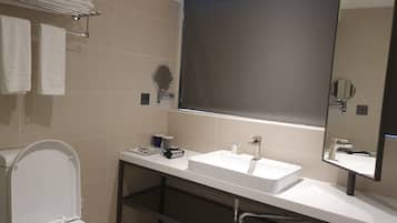 Ein modernes Badezimmer mit Toilette, Waschbecken und großem Spiegel.