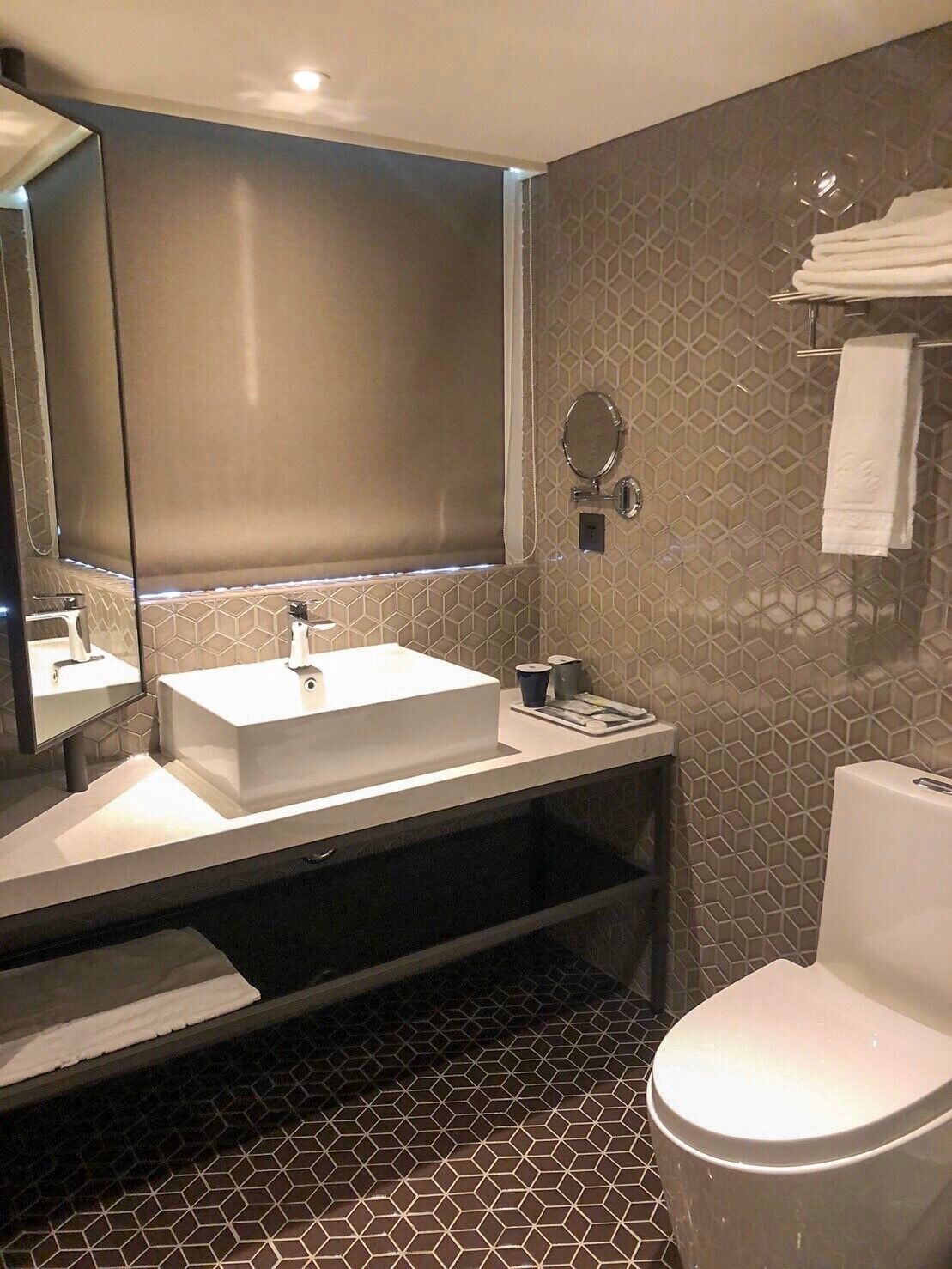 A modern bathroom with a rectangular sink, a toilet, and a large mirror.