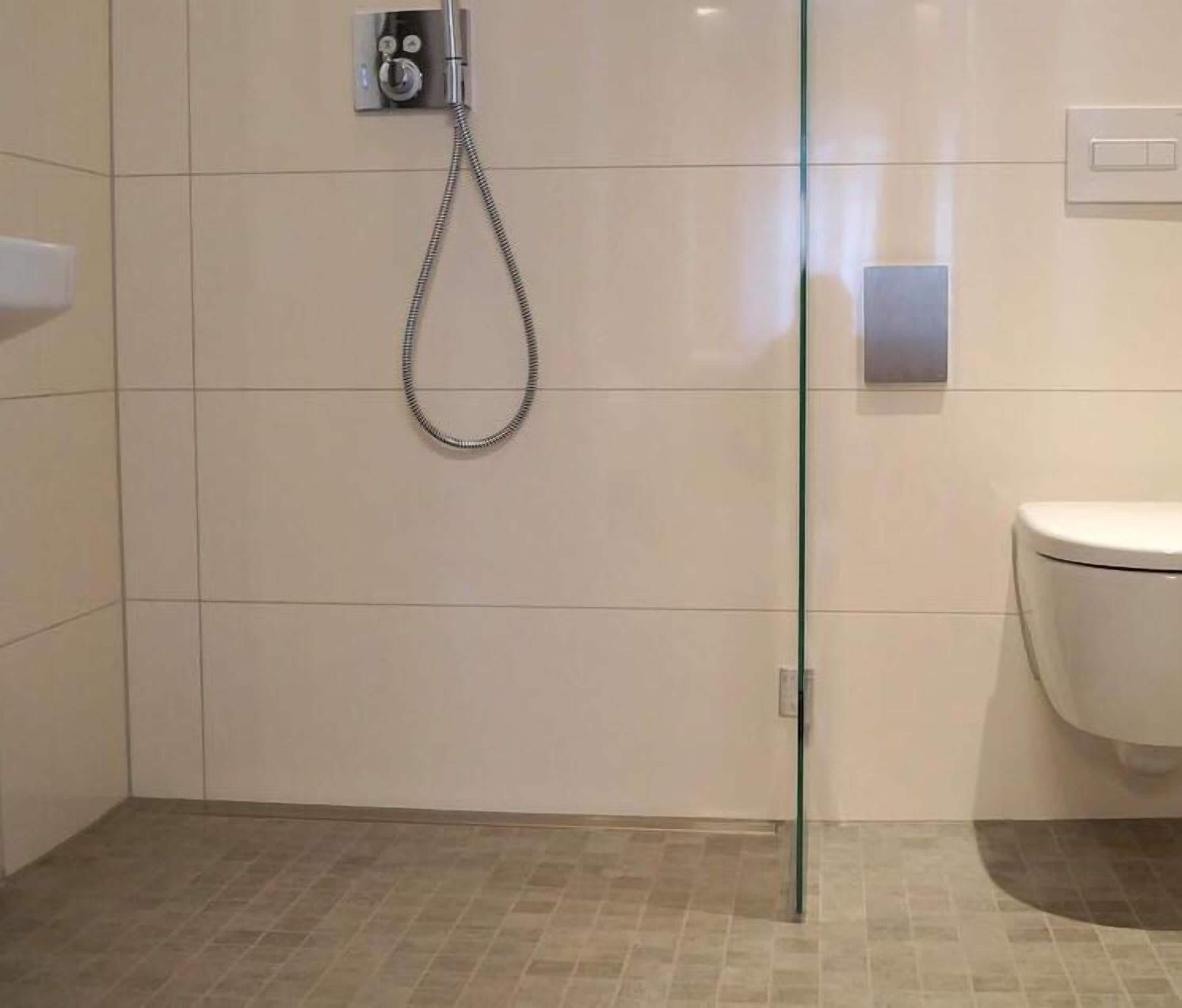 Un baño moderno con cabina de ducha de vidrio, inodoro y panel de control para la ducha.