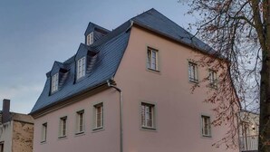Un edificio de varios pisos con fachada rosa, múltiples ventanas y techo inclinado.