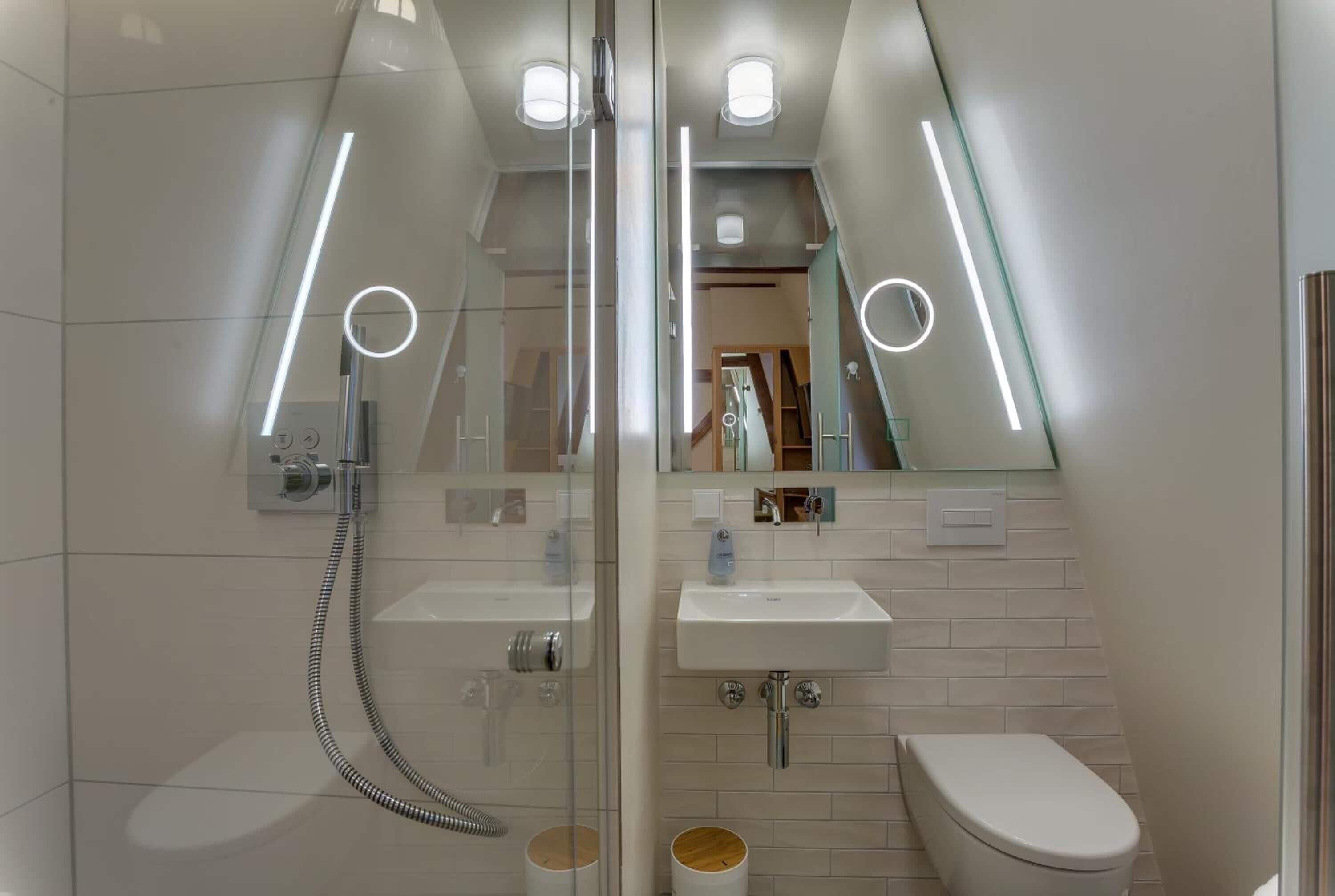 Une salle de bain moderne avec une douche à parois de verre, un lavabo blanc et des toilettes.