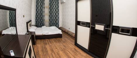 A hotel room with a bed, a dresser, a wardrobe, and a chandelier.