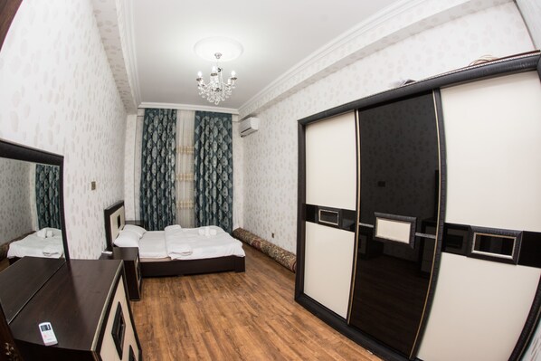 A hotel room with a bed, a dresser, a wardrobe, and a chandelier.