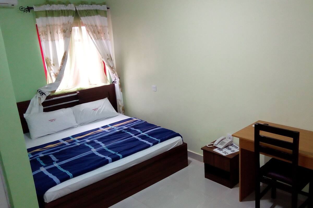 A bedroom with a bed, a desk, and a chair.