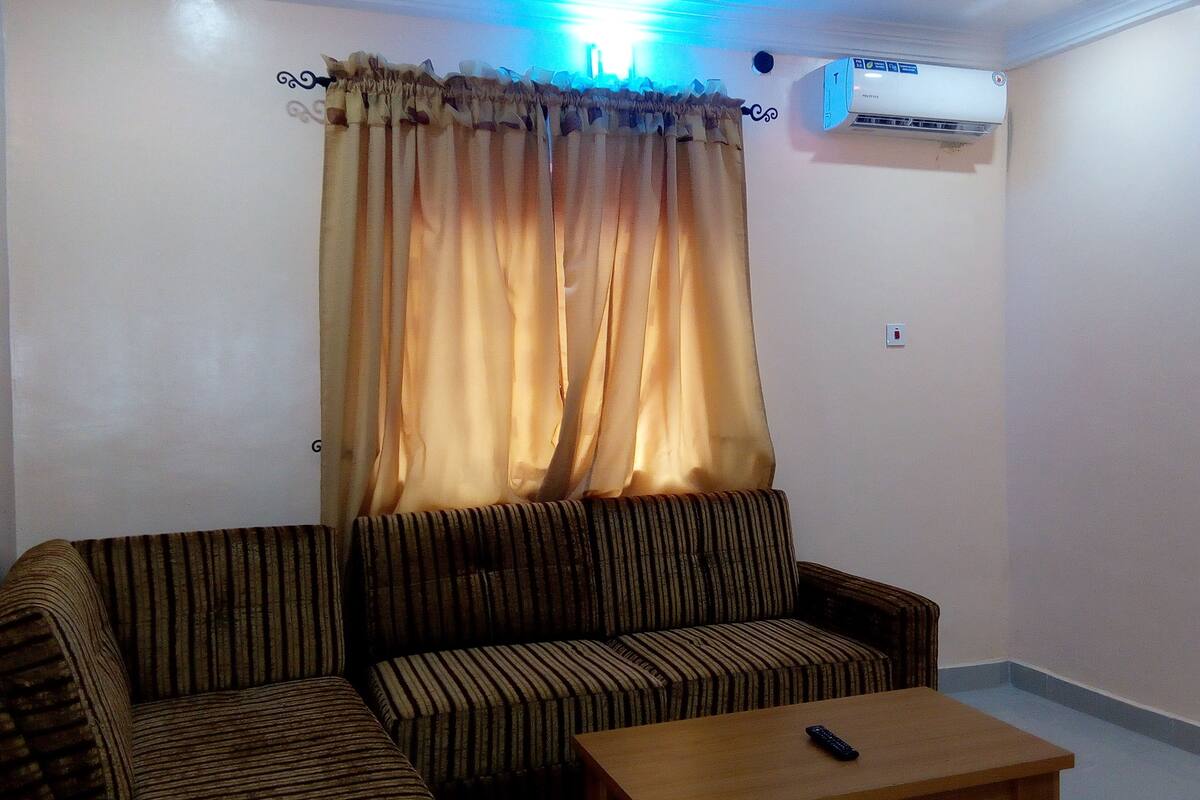 A living room with a sofa, a coffee table, and an air conditioning unit on the wall.