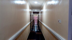A narrow, well-lit hallway with a checkered floor, leading to a room with a striped curtain. - Denposon Royal Hotel (Lagos)