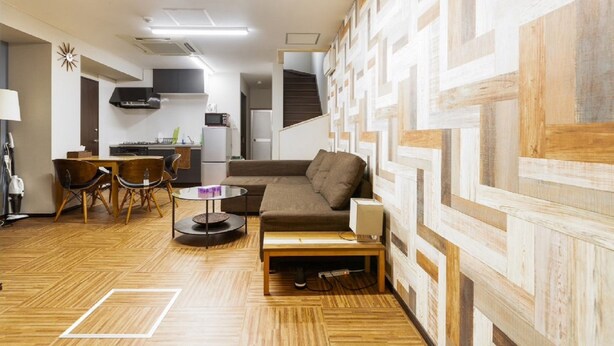 Un espacio habitable compacto con sofá, una mesita, una silla y zona de cocina.